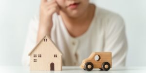 A person in a white shirt is observing a wooden toy house and car on a table, reflecting on understanding your rights when it comes to selling tenanted property.