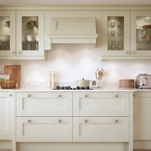 A modern, upgraded kitchen with cream cabinetry, a gas stove, glass fronted upper cabinets, utensils in a jar, and small appliances on a white countertop—perfect for letting your property faster.
